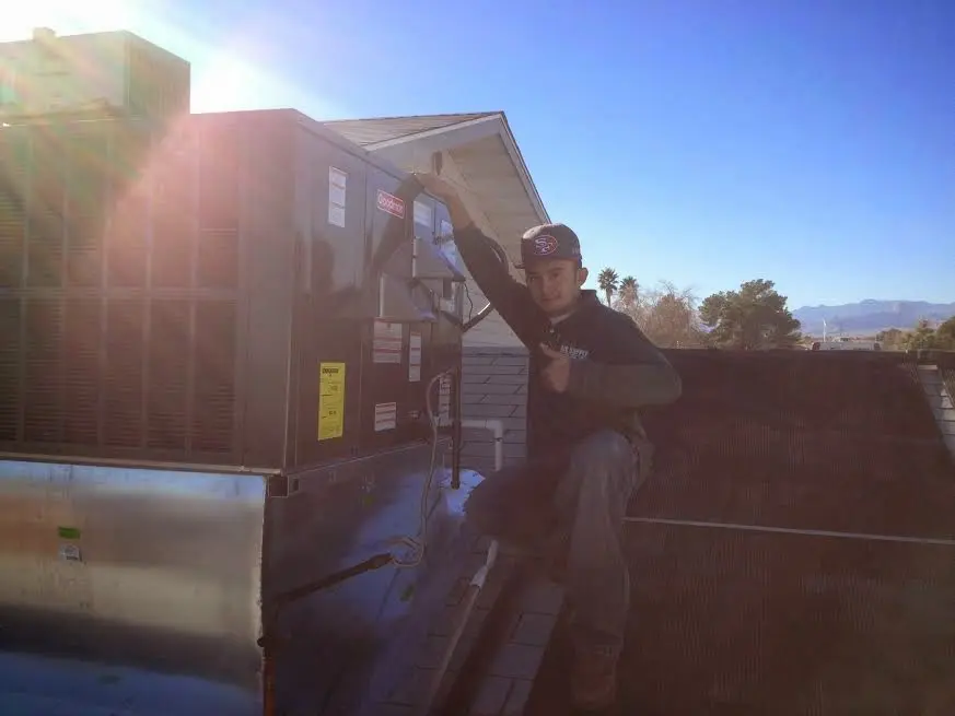 HVAC technician performing AC Tune-Up on a rooftop unit in Charlestown